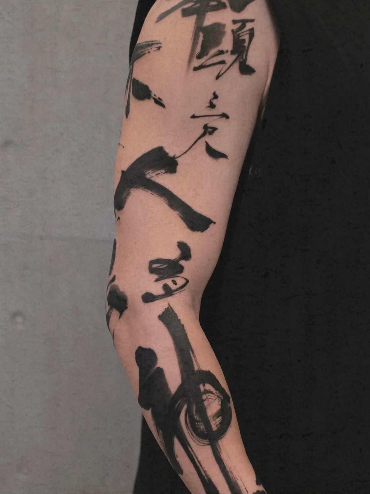 Close-up of a bold black Chinese calligraphy sleeve tattoo
